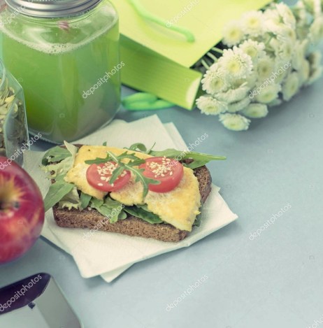 Healthy vegetarian Breakfast. Sandwich grain bread tofu cheese, detox smoothie, pumpkin seeds, cherry tomatoes, natural flowers, blue background, notebook. Lunch box with soup for lunch